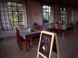 A dining area with checkered tablecloths, wooden chairs, and a chalkboard sign indicating a temperature of 21°C. - Lago Resort (Kisumu)