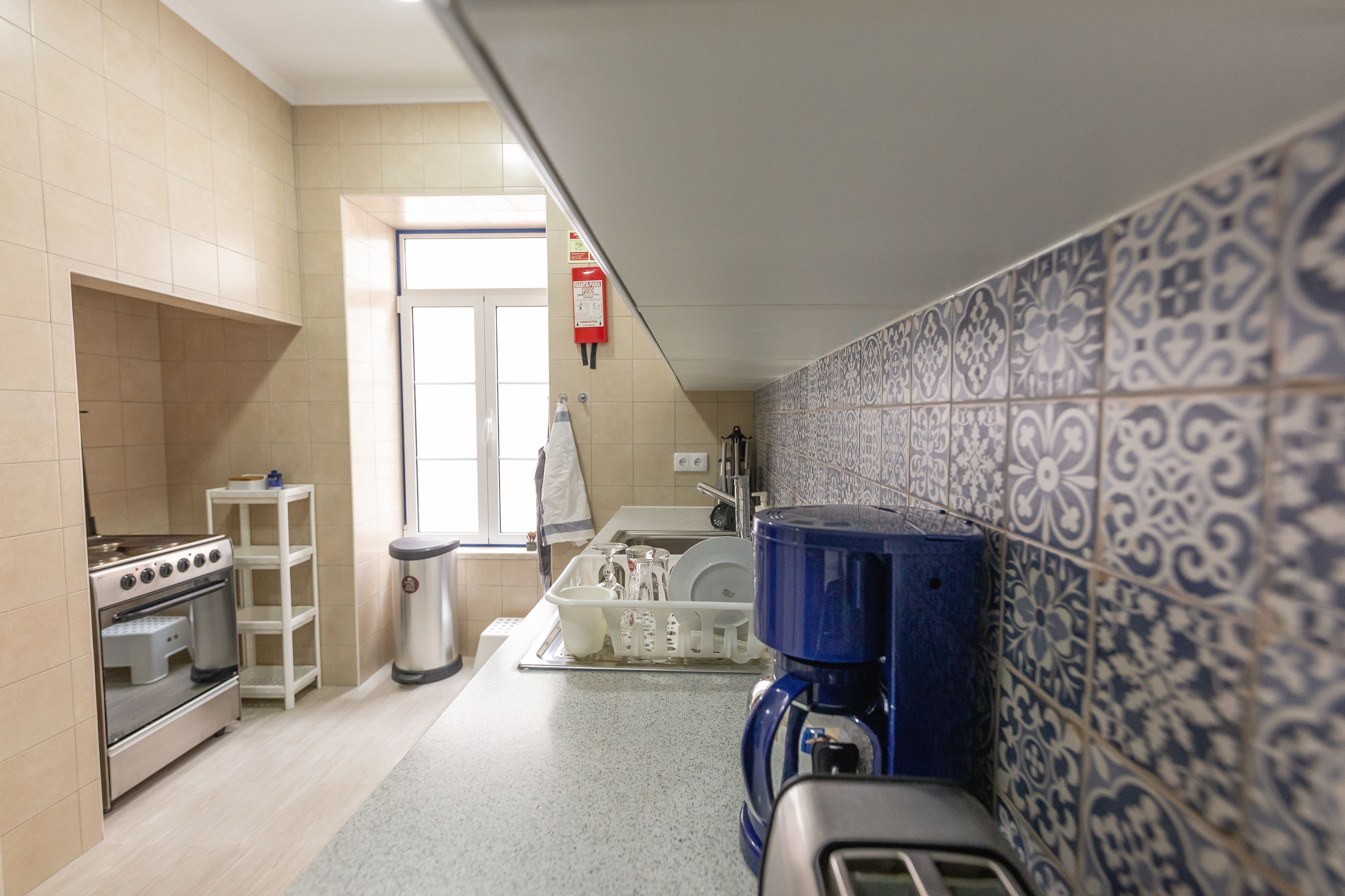 A kitchen with a stove, oven, sink, and coffee maker.