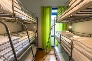 A bunk bed room with metal railings, a wooden floor, and a green curtain. - Help Yourself Hostels Parede (Cascais)