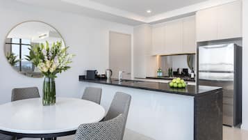 A modern kitchen with a central island, a round dining table with patterned chairs, and a large mirror on the wall.