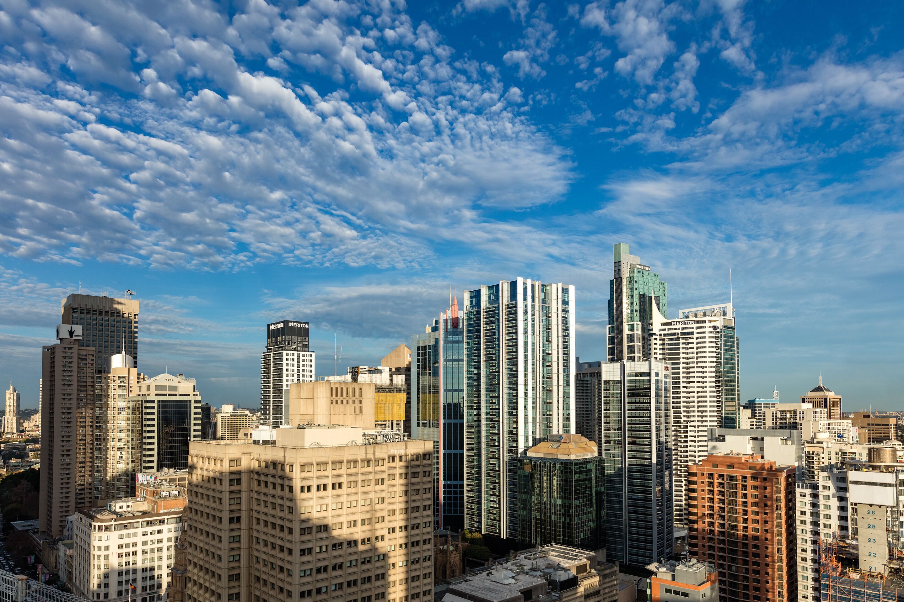 A cityscape with multiple high-rise buildings, including a prominent skyscraper with a unique top design.