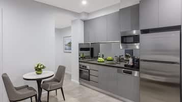 Una cocina moderna con gabinetes grises, electrodomésticos de acero inoxidable y una mesa redonda con dos sillas.