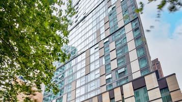 A modern high-rise building with a glass facade, large windows, and a mix of beige and dark brown exterior panels.