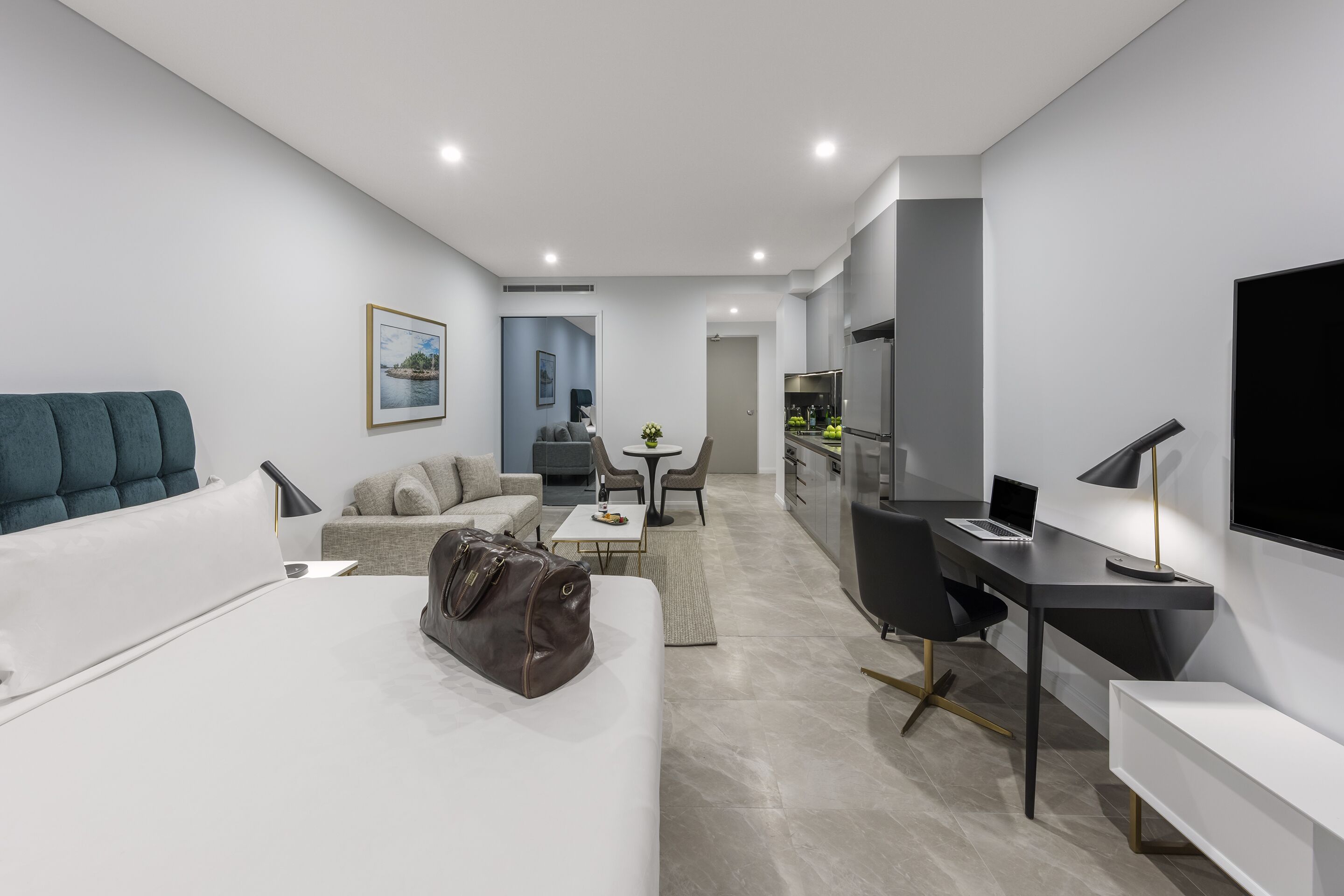 Una habitación de hotel moderna con cama, escritorio, silla, sofá y televisor.