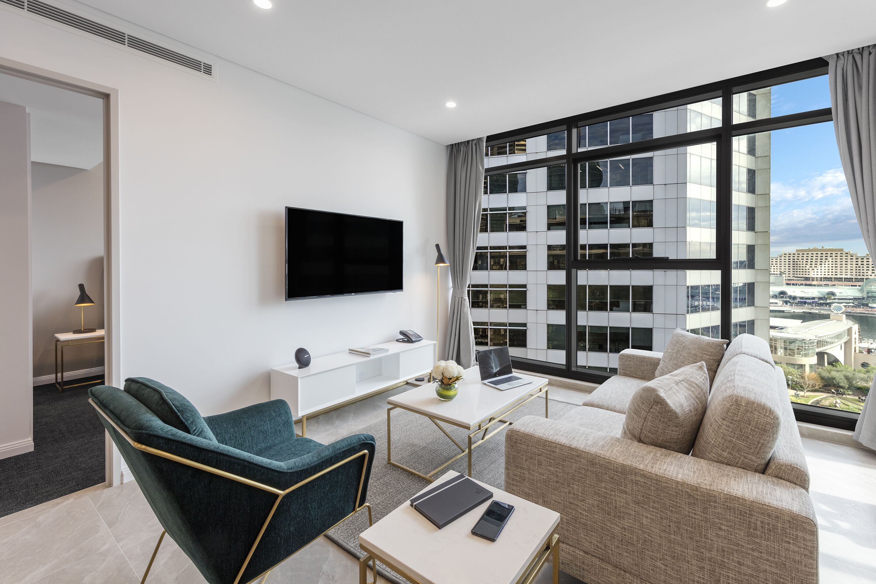 Een moderne hotelkamer met een groot raam, een flatscreen televisie, een bank, een bureau en een stoel.