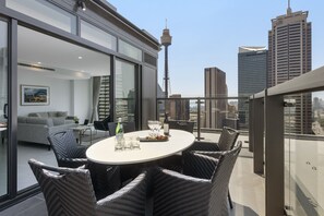Een modern terras op het dak met een ronde tafel, rieten stoelen en een glazen balustrade.