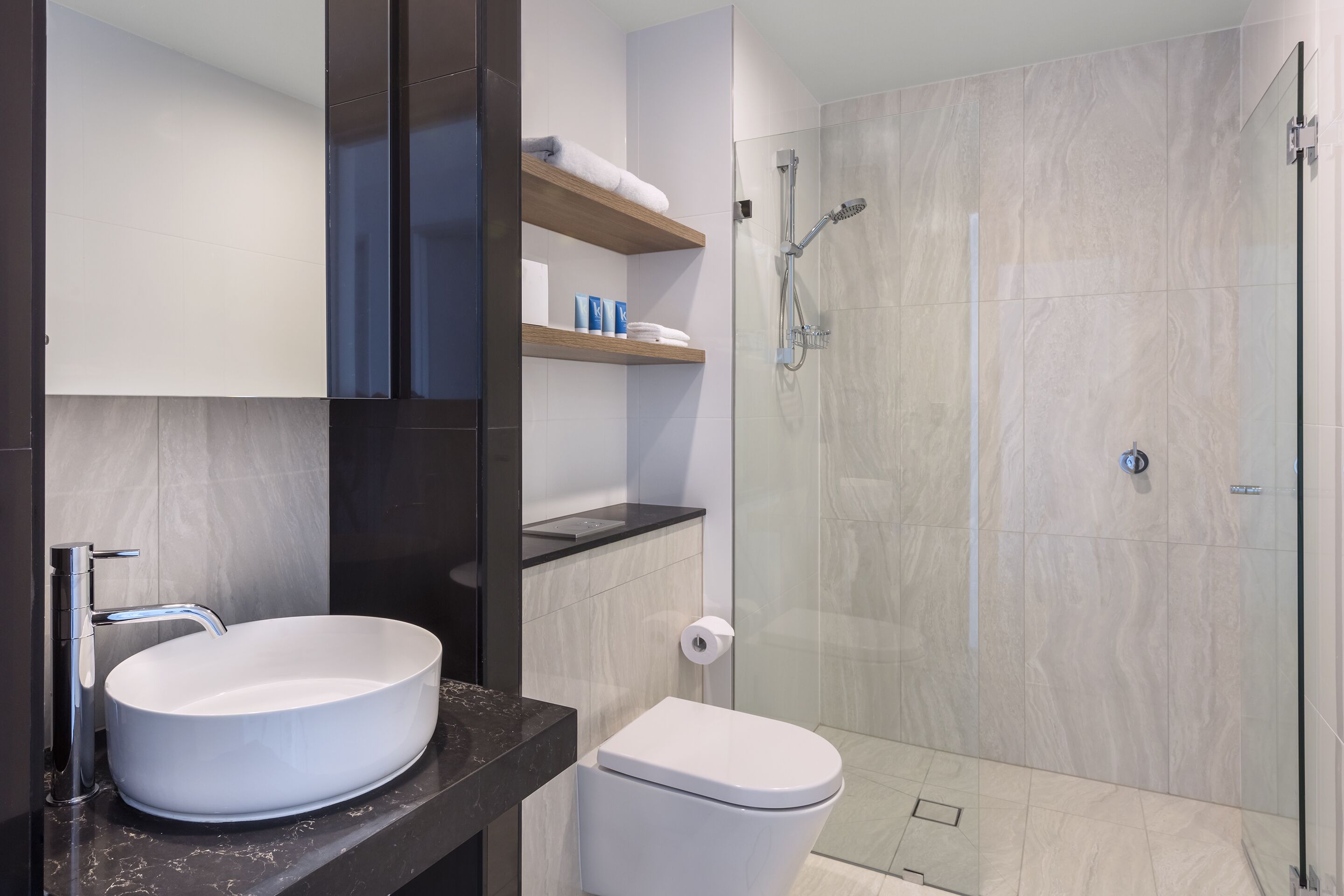 A modern bathroom with a white sink, a toilet, and a glass-enclosed shower.