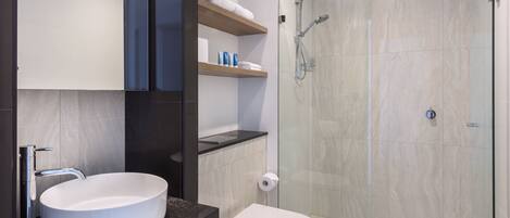 A modern bathroom with a white sink, a toilet, and a glass-enclosed shower.