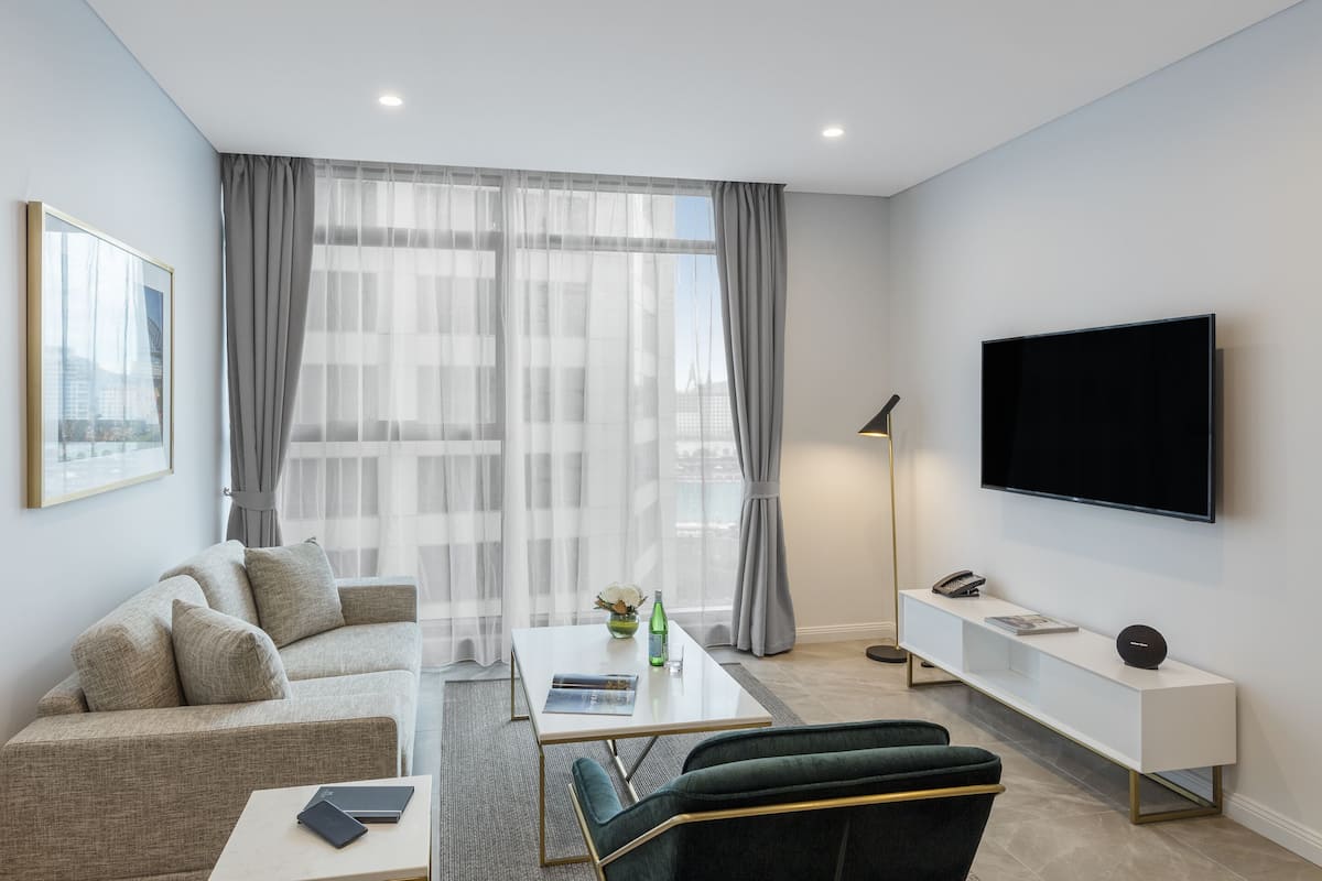 Una sala de estar moderna con un sofá, una mesa de centro y un televisor de pantalla plana montado en la pared.