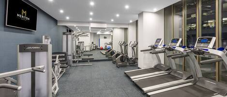 A gym with treadmills, weight machines, and a mirrored wall.
