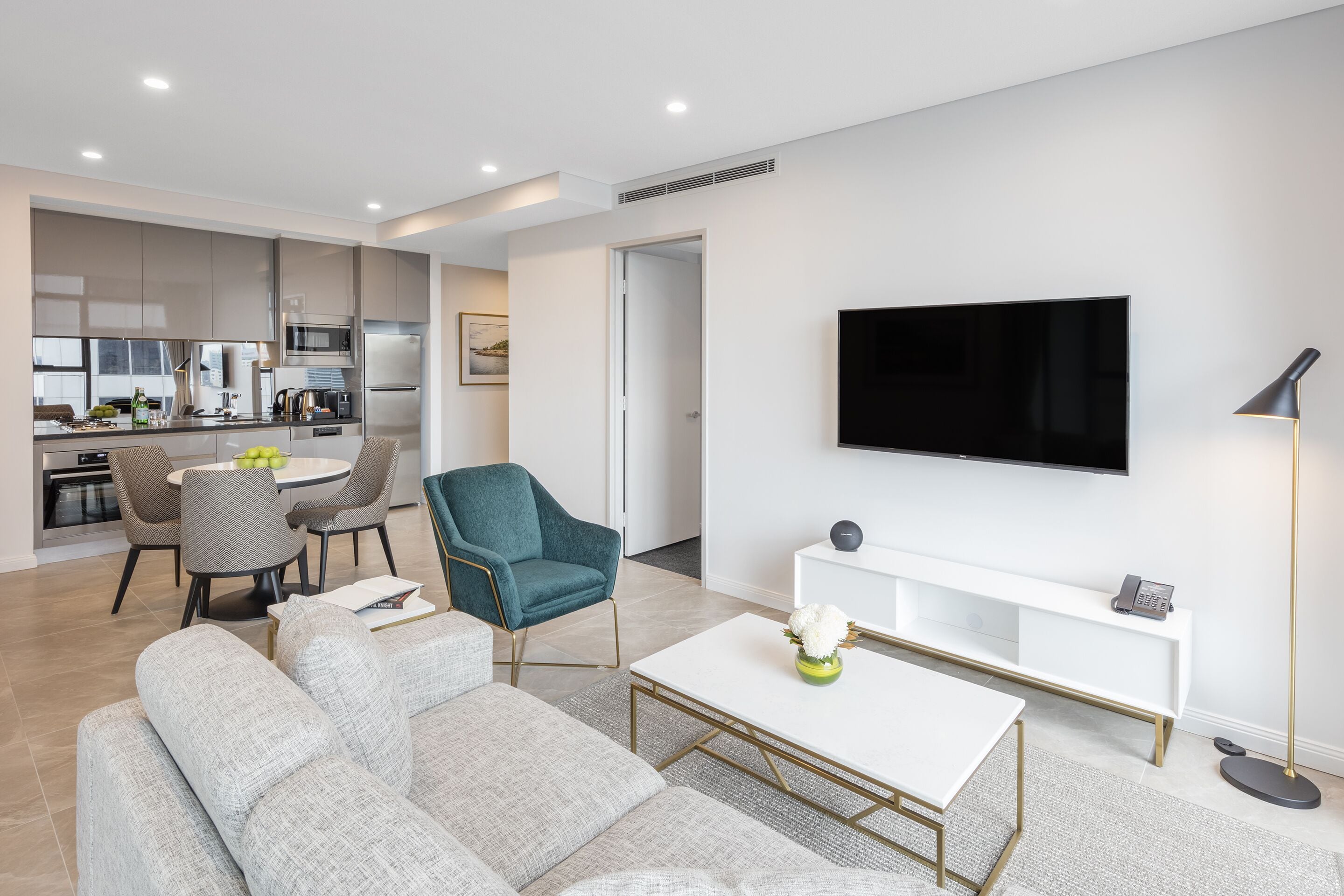 A modern living room with a sofa, coffee table, and a TV mounted on the wall.