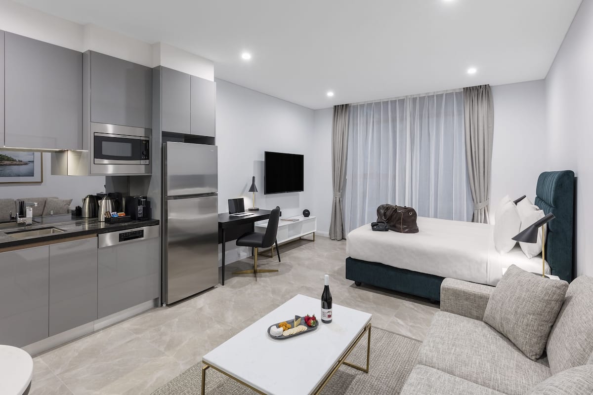 Una habitación de hotel moderna con kitchenette, una cama, un escritorio y una sala de estar.