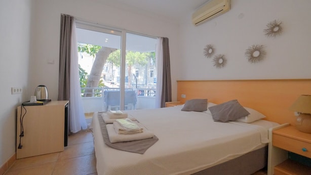 A hotel room with a bed, a desk, a chair, and a view of the outside. - Mimosa Pension (Kas)