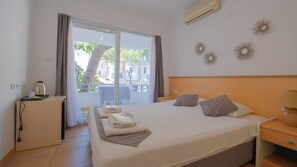 Une chambre d’hôtel avec un lit, un bureau, une chaise et une vue sur l’extérieur.