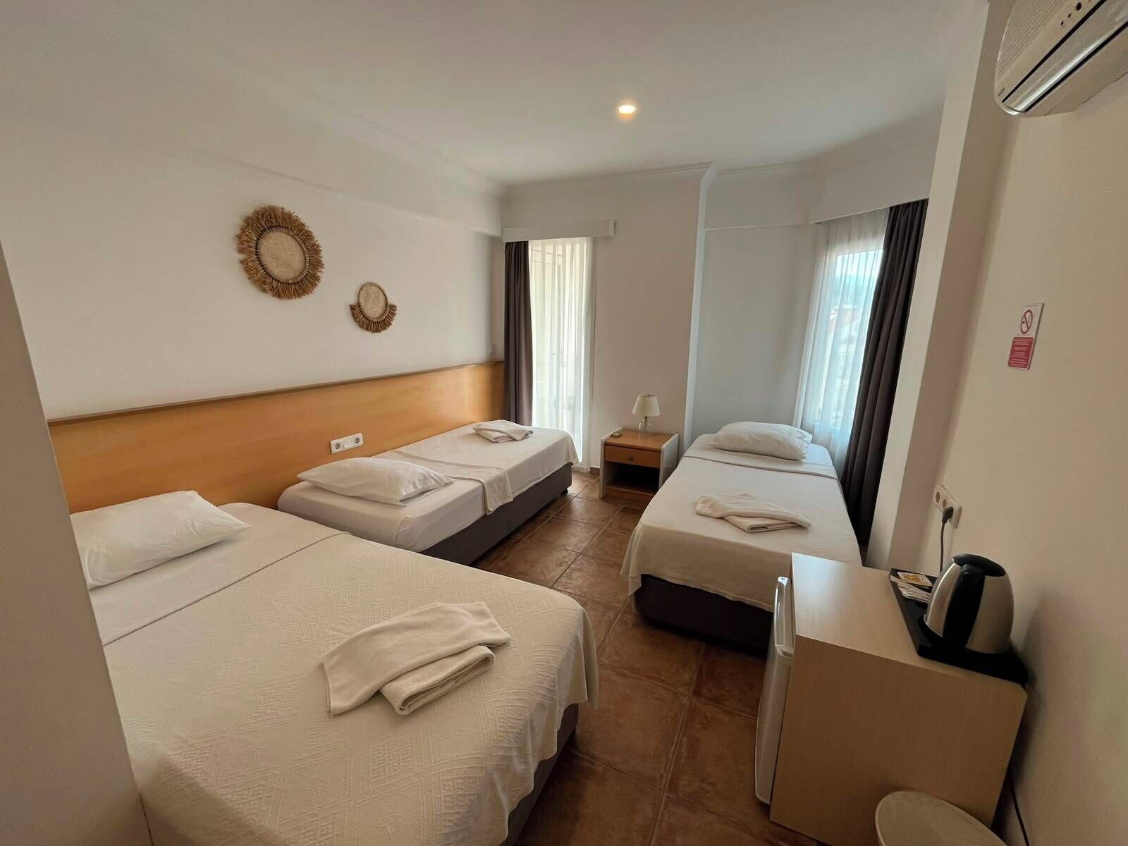 Una habitación de hotel con tres camas, un escritorio y un minibar.
