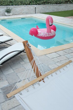 Una piscina al aire libre de temporada, tumbonas