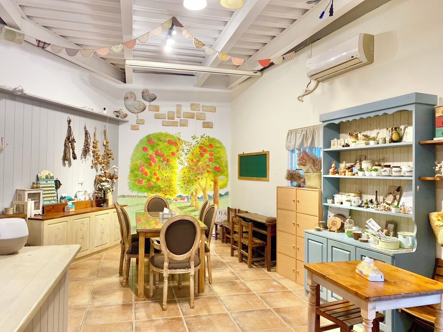 Une pièce chaleureuse avec une table à manger en bois, des chaises, un petit coin cuisine et des étagères remplies de divers objets.