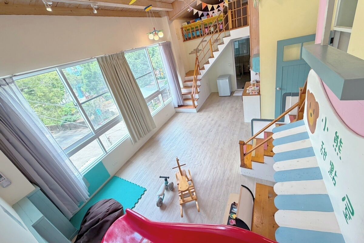 A multi-level interior with a staircase, a slide, and a play area.