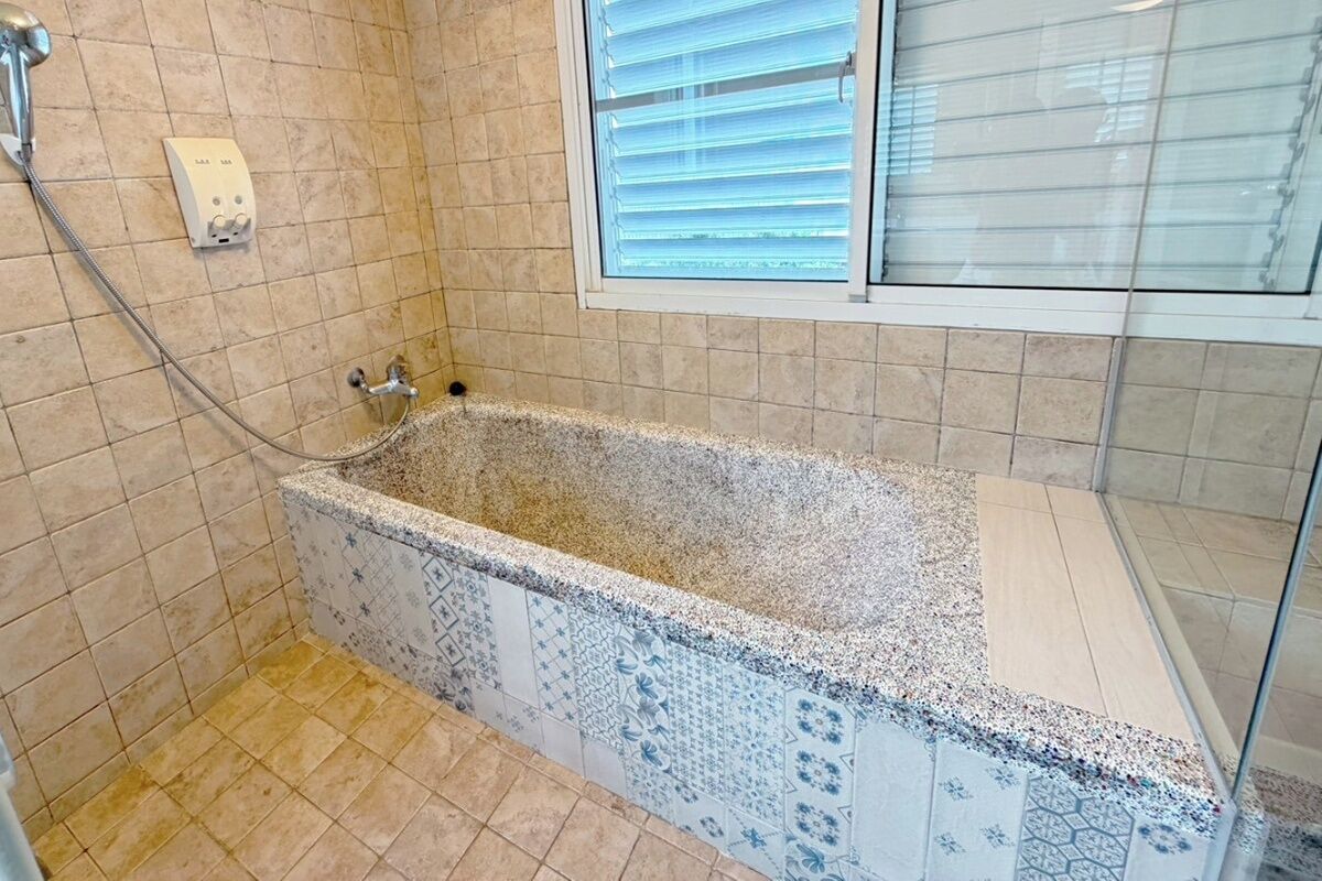 A bathroom with a freestanding bathtub, a shower, and a window with blinds.