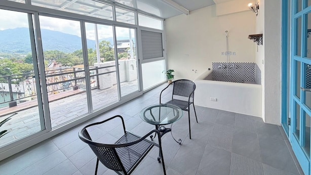 A balcony with a glass table and chairs, a blue door, and a view of mountains. - Village Villa B&B (Zhuqi)