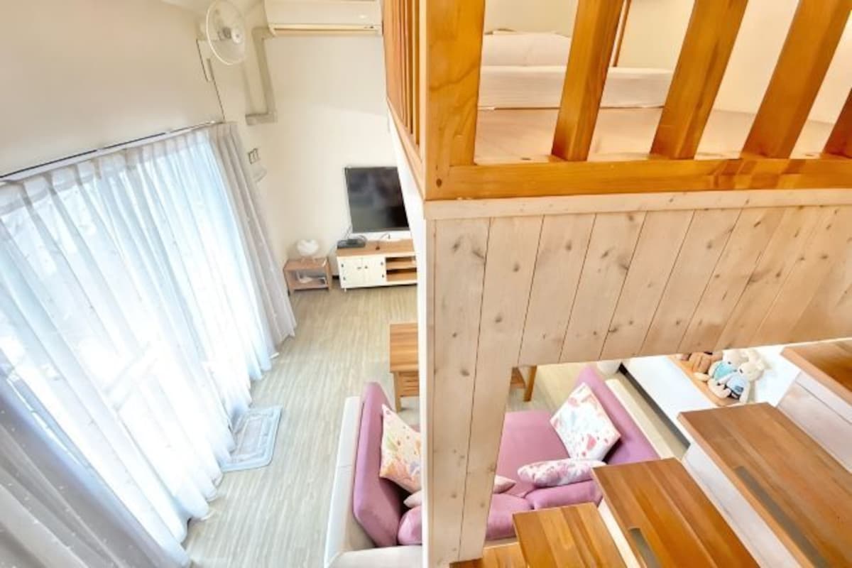 A room with a wooden bunk bed, a sofa, a television, and a small table.