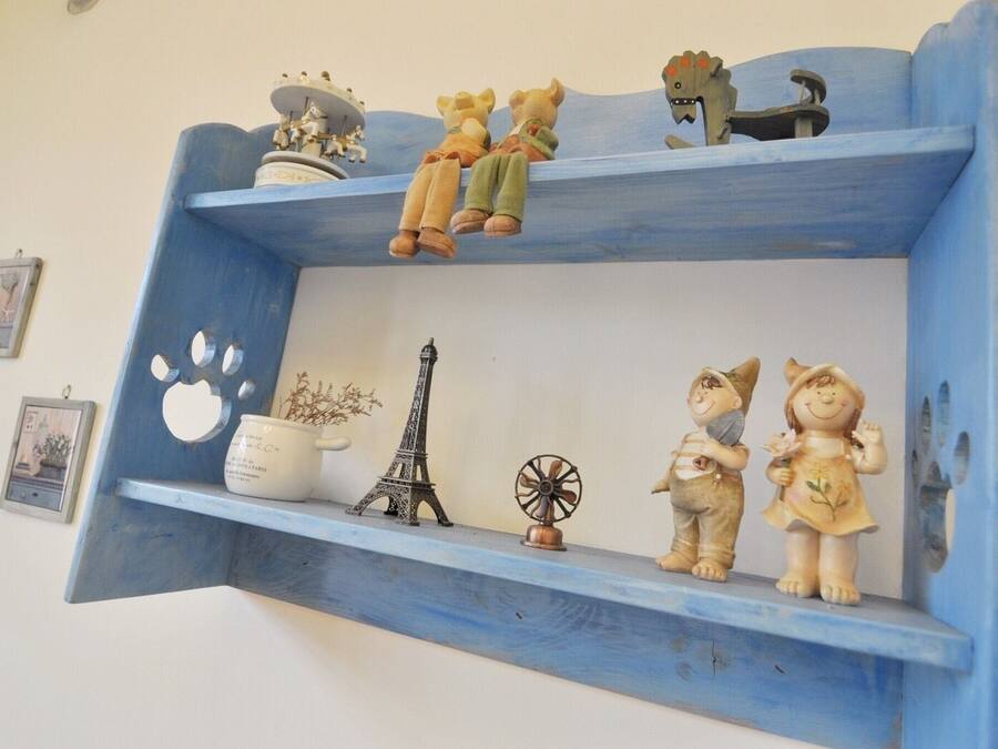 Een blauwe plank met diverse decoratieve objecten, waaronder beeldjes, een klein model van de Eiffeltoren, een waaier en een potplant.