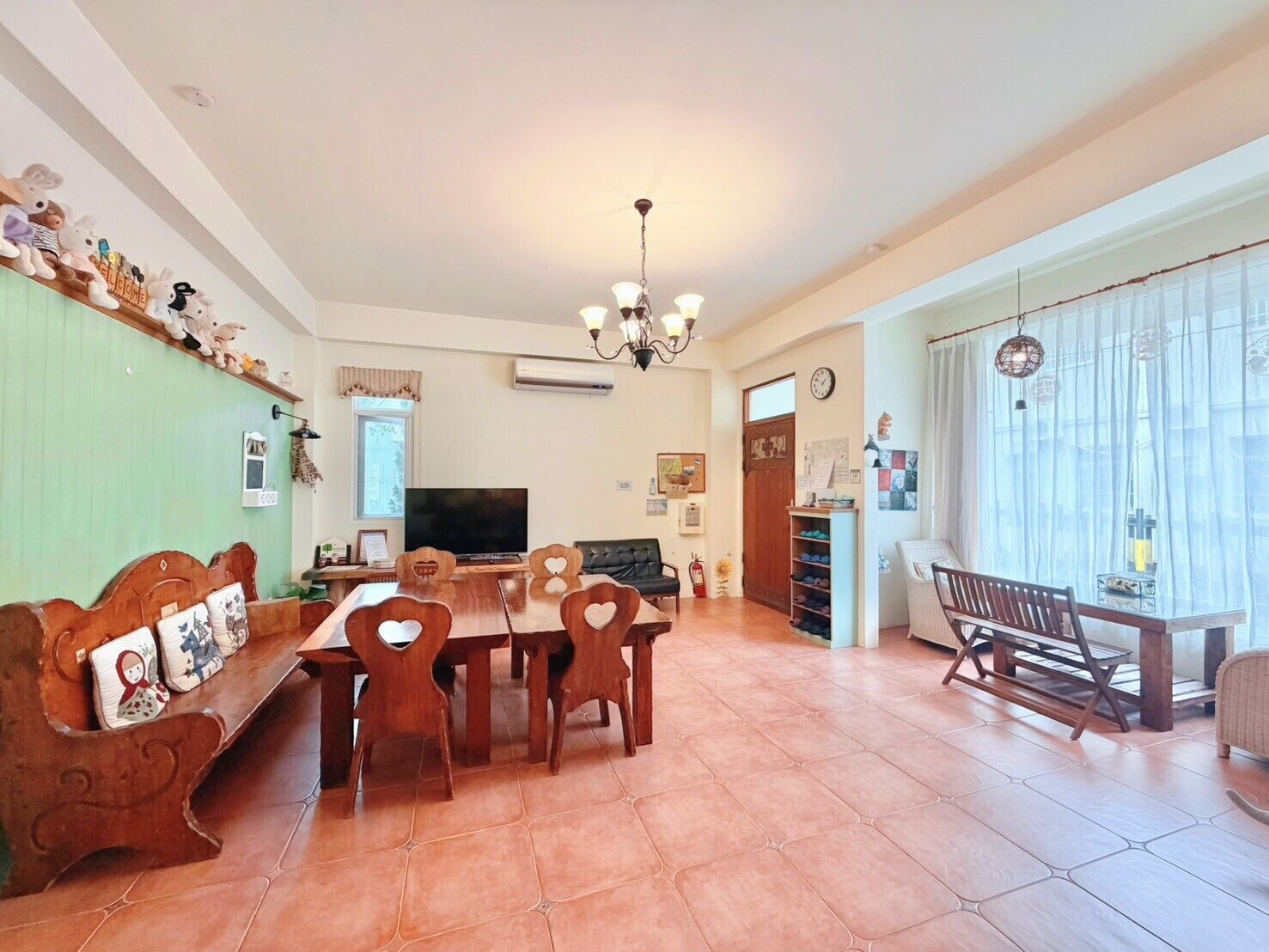 Un comedor con mesa y sillas de madera, televisor y candelabro.