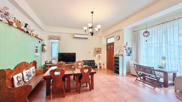 Un comedor con mesa y sillas de madera, televisor y candelabro.