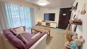 A living room with a sofa, a coffee table, a TV, and a teddy bear on a shelf. - Village Villa B&B (Zhuqi)