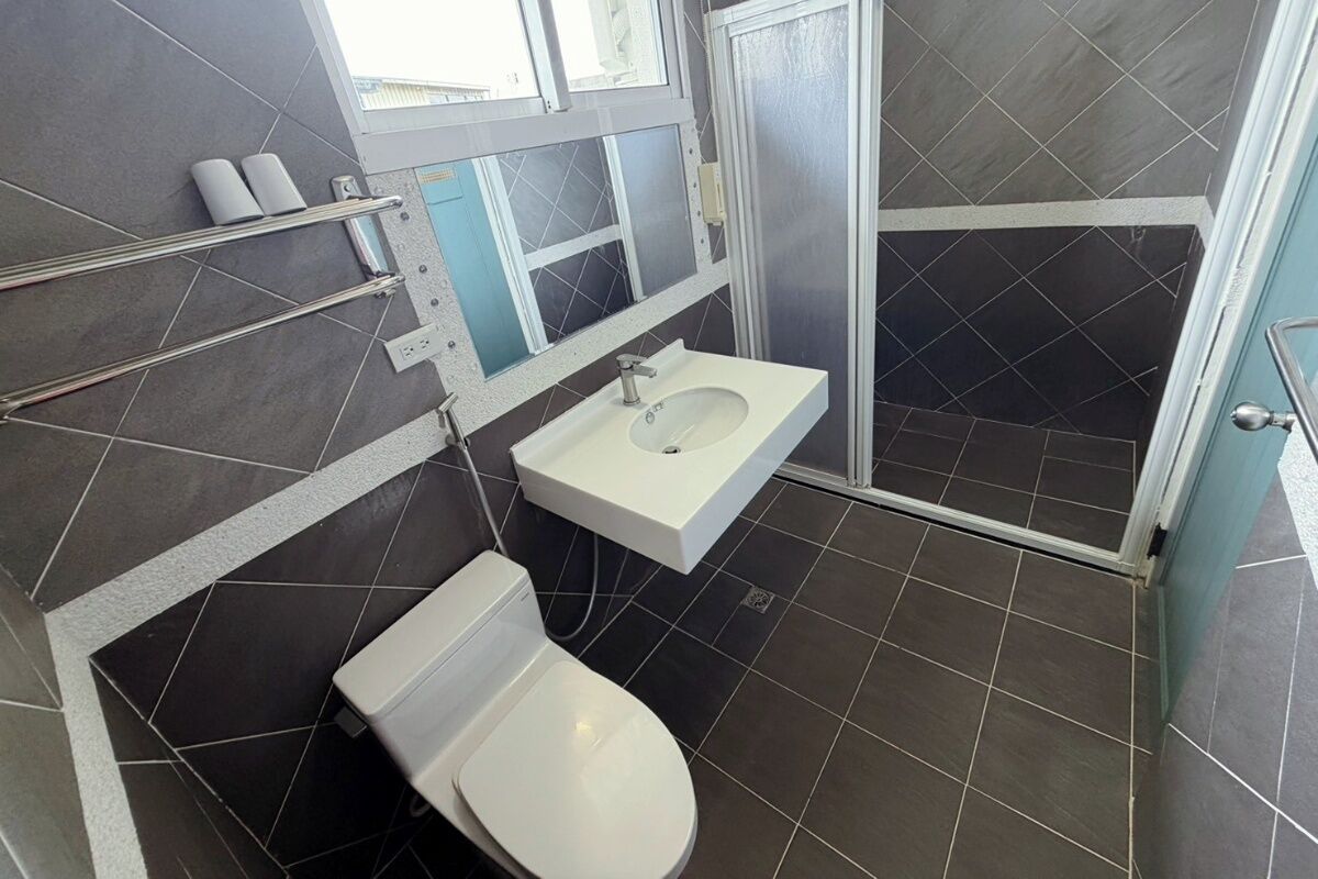 A bathroom with a white toilet, a white sink, and a shower area.