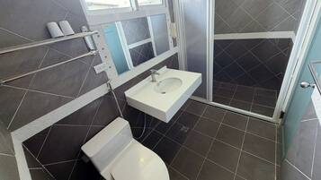 A bathroom with a white toilet, a white sink, and a shower area.