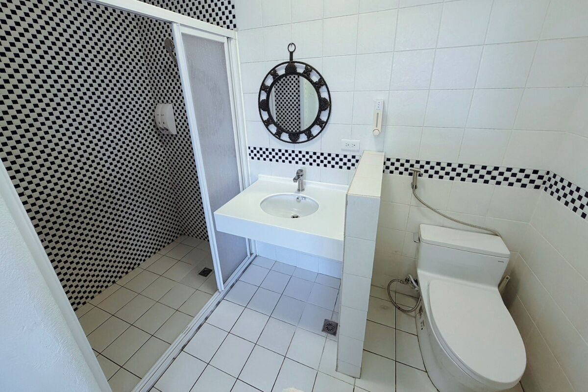 A bathroom with a white sink, a toilet, and a mirror with a decorative frame.