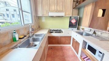A compact kitchen with a gas stove, two sinks, wooden cabinets, and a window.
