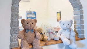 A room with a brick archway, a wooden shelf with teddy bears, and a blue shelf with various items. - Village Villa B&B (Zhuqi)