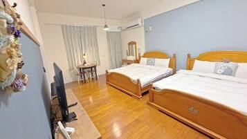 Habitación de hotel con dos camas de madera, un escritorio con computadora, una silla y una ventana con cortinas.