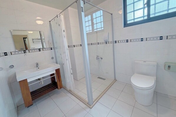 Un baño con cabina de ducha de vidrio, un lavabo blanco y un inodoro.