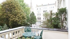 Un balcon avec une balustrade en fer forgé, une petite table et des chaises.