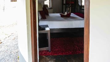 Une pièce avec un lit recouvert d’une moustiquaire, un banc et une moquette rouge.