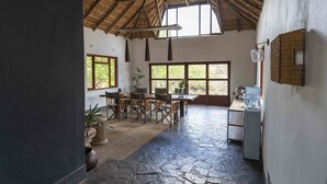 A spacious room with a thatched roof, large windows, a dining area with a table and chairs, and a water dispenser. - Ku Sungula Safari Lodge (Hoedspruit)