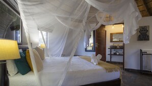A bed with a canopy, bedside lamps, and a bedside table. - Ku Sungula Safari Lodge (Hoedspruit)