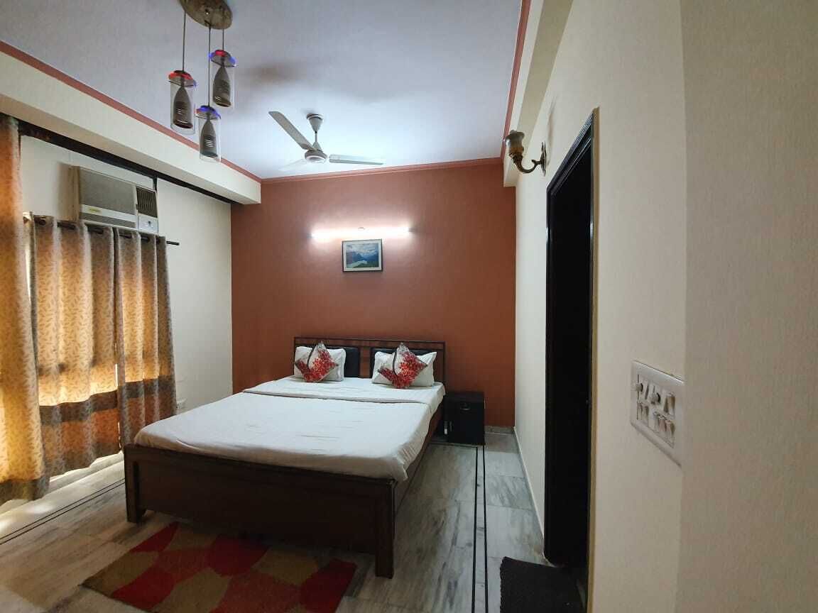 A bedroom with a bed, curtains, a ceiling fan, and a wall-mounted light fixture.