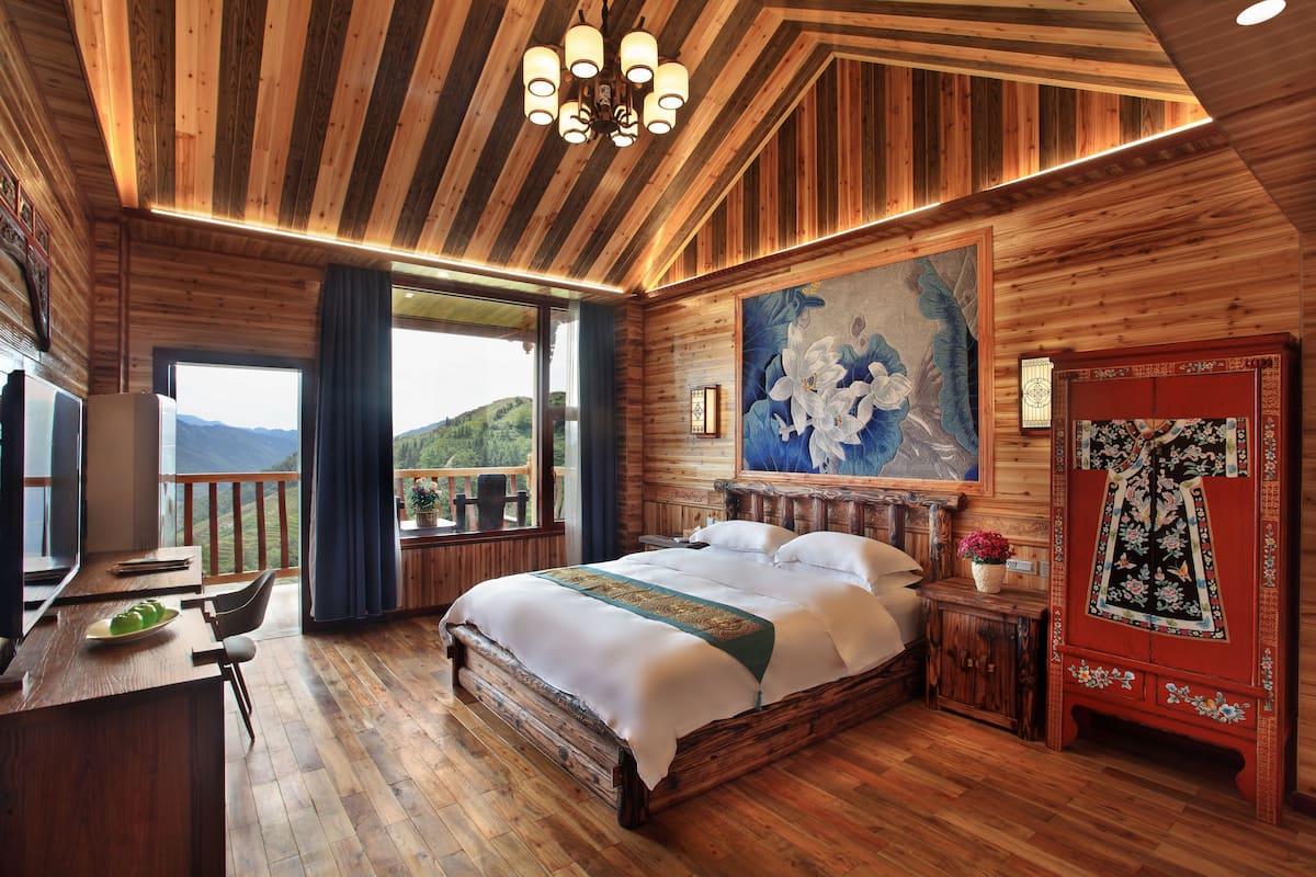 Una habitación de madera con una cama, un escritorio y vistas al exterior.