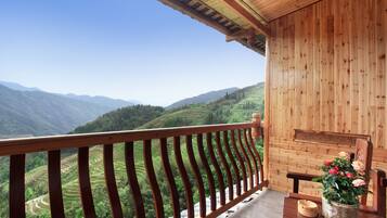Un balcón de madera con vistas a campos escalonados y montañas.