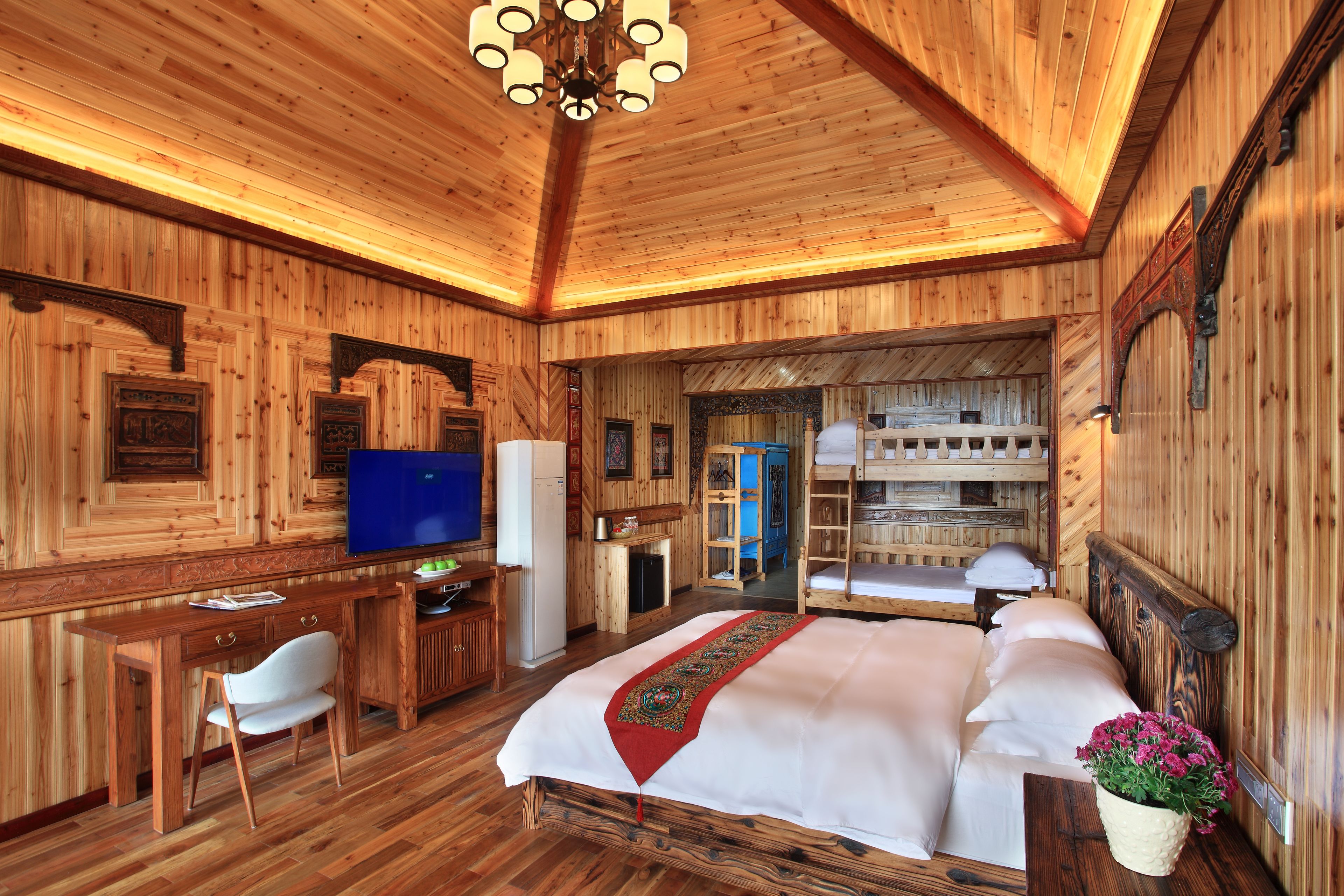 Una habitación con decoración de madera, que incluye una cama, un escritorio, una silla y un televisor.