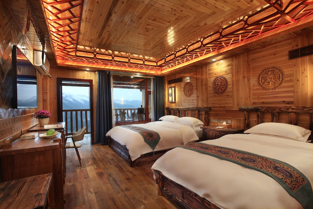 Una cabaña de madera con dos camas, un escritorio de madera y un balcón con vistas a la montaña.
