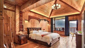 Une chambre à coucher décorée dans un style rustique, avec un grand lit, une table de chevet et une vue sur les montagnes depuis un balcon.