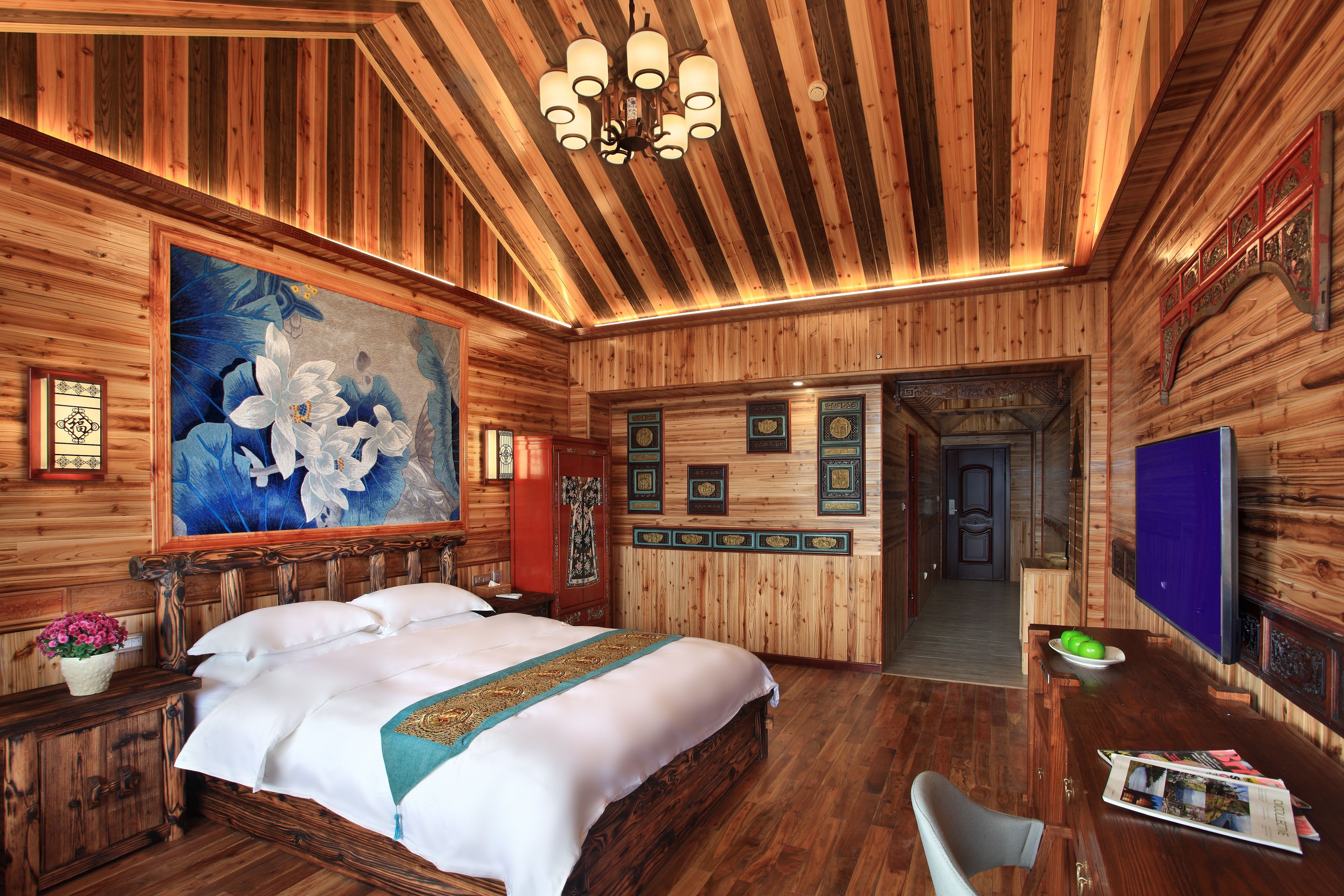 Ein holzgestalteter Raum mit einem großen Bett, einem Schreibtisch und einem Blumenbild.