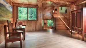 Un intérieur en bois comprenant un coin repas, un escalier et de grandes fenêtres.