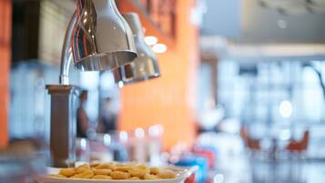 A buffet table with a plate of pastries and a hanging light fixture.