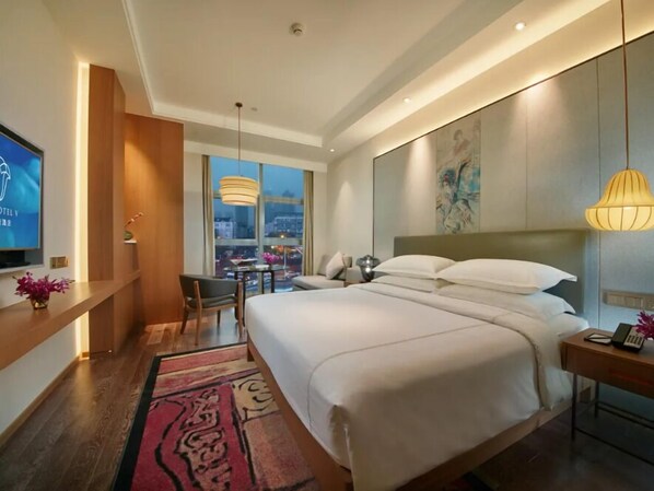 Una habitación de hotel moderna con una cama grande, un escritorio y un televisor.